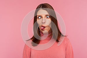 Closeup portrait of funny crazy woman crossing eyes and showing tongue, having fun making dumb face expression, fooling face