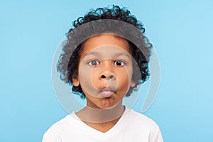 Closeup portrait of funny goofy little boy with curly hair making fish face with pout lips and big eyes