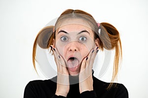 Closeup portrait of a funny redhead teenage girl with childish hairstyle sticking out her tongue isolated on white backround