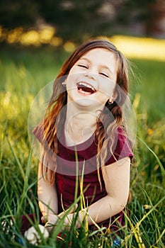 Closeup portrait of funny smiling laughing young Caucasian girl outdoors. Cute adorable kid child having fun outside. Happy