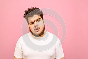 Closeup portrait of a funny surprised fat man with beard and curly hair on a pink background, looks into the camera with a look of