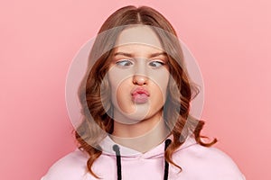 Closeup portrait of funny teenager girl with curly hair making silly face with crossed eyes, awkward stupid expression, having fun