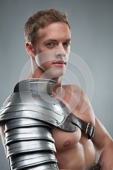 Closeup portrait of Gladiator in armour over grey