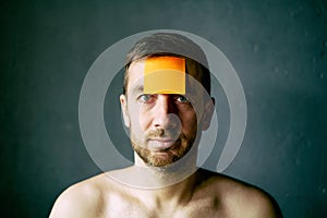 Closeup portrait of half naked man with sticky note on his forehead