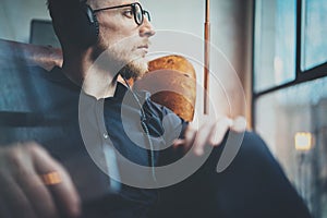 Closeup portrait handsome bearded man in headphones listening to music via mobile phone at modern loft.Guy sitting in