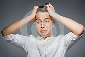 Closeup Portrait of handsome boy with astonished expression while standing against grey background