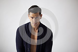 Closeup portrait of handsome brunette young man in black sweater, over white background.