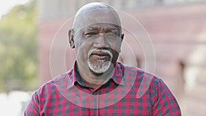 Closeup portrait of handsome face of elderly black man with smile. Friendly mature bearded African American male in