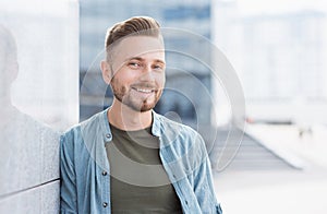 Closeup portrait of handsome smiling young man. Cheerful businessman in a city
