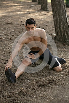 Closeup portrait of a handsome sportsman doing stretching exercises in the park. Healthy active lifestyle concept