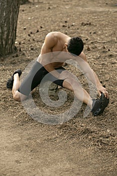 Closeup portrait of a handsome sportsman doing stretching exercises in the park. Healthy lifestyle concept