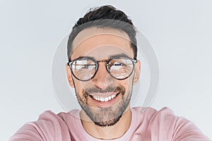 Closeup portrait of handsome young happy smiling bearded male model look at the camera, wears round trendy glasses with toothy