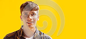 Closeup portrait of handsome young man, teen looking at camera isolated on bright yellow studio backgroud. Human