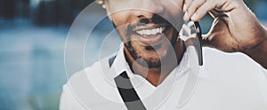 Closeup portrait of happy American African man using mobile phone to call his friends at sunny city.Concept of happy