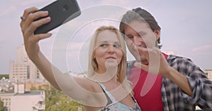 Closeup portrait of happy attractive caucasian couple taking selfies on phone hugging standing on balcony of house