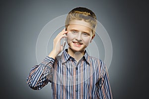 Closeup Portrait of happy boy with mobile or cell phone on gray background