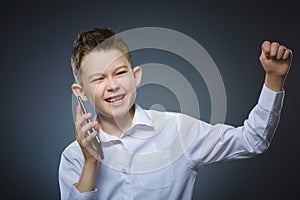 Closeup Portrait of happy boy with mobile or cell phone on gray background