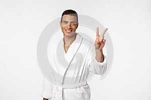 Closeup portrait happy, excited, successful young man giving peace, victory or two sign, isolated white background.