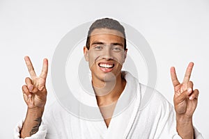 Closeup portrait happy, excited, successful young man giving peace, victory or two sign, isolated white background.