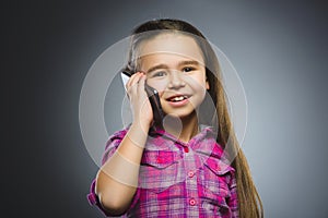 Closeup Portrait of happy girl with mobile or cell phone on gray background