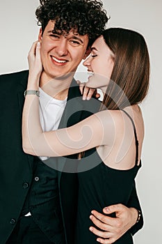 Closeup portrait of happy loving couple in black outfits for event, gray studio background. Smiling guy and elegant girl