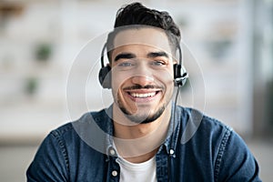 Closeup portrait of happy middle-eastern guy with headset having conversation
