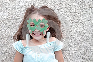 Closeup portrait of a happy preteen caucasian girl in an emerald leprechaun glasses in the form of clover. St. Patrick`s Day