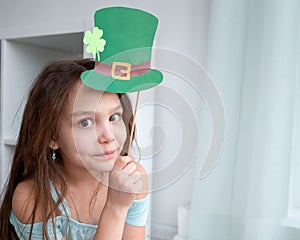 Closeup portrait of a happy preteen caucasian girl in an emerald leprechaun St. Patrick`s Day hat