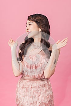 Closeup portrait of happy pretty young woman in pink dress over pink background