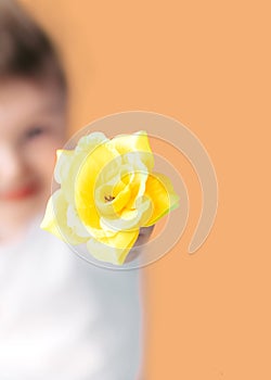 Closeup portrait happy smiling boy with orange rose. Beautiful little boy toddler giving a flower Mother`s day concept. boy