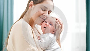 Closeup portrait of happy smiling mother holding and looking on her newborn baby boy. Concept of family happiness and