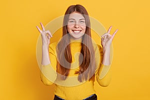 Closeup portrait of happy smiling woman showing rock sign, looking directly at camera, wearing casual attire, being in good mood,