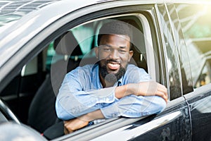 Closeup portrait happy smiling young african man sitting in his new car excited ready for trip