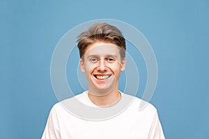 Closeup portrait of a happy young man smiling on gray background