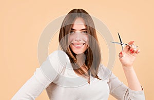 Closeup portrait of happy young woman having her hair cut with scissors at home. Beautiful girl with straight hair with
