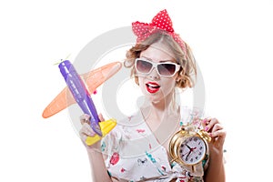 Closeup portrait of having fun playing with airplane & showing alarm clock beautiful blond young woman pinup girl in sunglasses