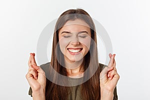 Closeup portrait hopeful beautiful woman crossing her fingers, open eyes, hoping, asking best isolated on gray wall