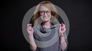 Closeup portrait of hopeful middle-aged caucasian woman having her fingers crossed and praying