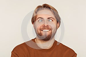 Closeup portrait of idiot, dumb bearded man looking cross-eyed with stupid smile, fooling around, making silly face