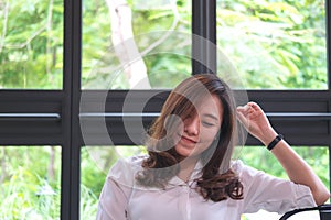 Closeup portrait image of beautiful Asian woman with smiley face and feeling good sitting in cafe with green nature