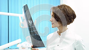 Closeup portrait of intellectual woman in white labcoat, looking at full body x-ray radiographic image, ct scan in the