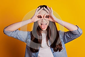 Closeup portrait of lady show ok signs cover eyes protrude tongue isolated yellow wall background photo