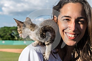 Closeup portrait of a Latin young woman with straight hair with a kitten on her shoulder