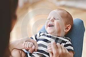 Closeup portrait of laughing newborn baby lying on mother`s lap