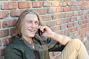 Closeup portrait of laughing young man talking on mobile phone outdoors