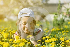 Closeup portrait of little cute girl lying with dandelions on the grass. Happy smiling girl lies on the grass among