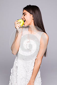 Closeup portrait of lovely young brunette woman biting juicy fresh delicious apple against gray background. Beautiful young lady e