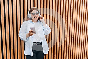 Closeup portrait of a lovely young girl listening to music through wireless earphones on wooden rustic background. Music