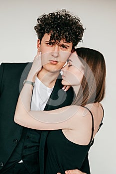 Closeup portrait of loving couple in black outfits for event, gray studio background. Handsome guy and elegant girl