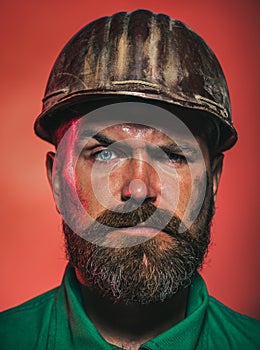 Closeup portrait of male builder in protective clothing and helmet. Construction worker in hard hat. Serious bearded man